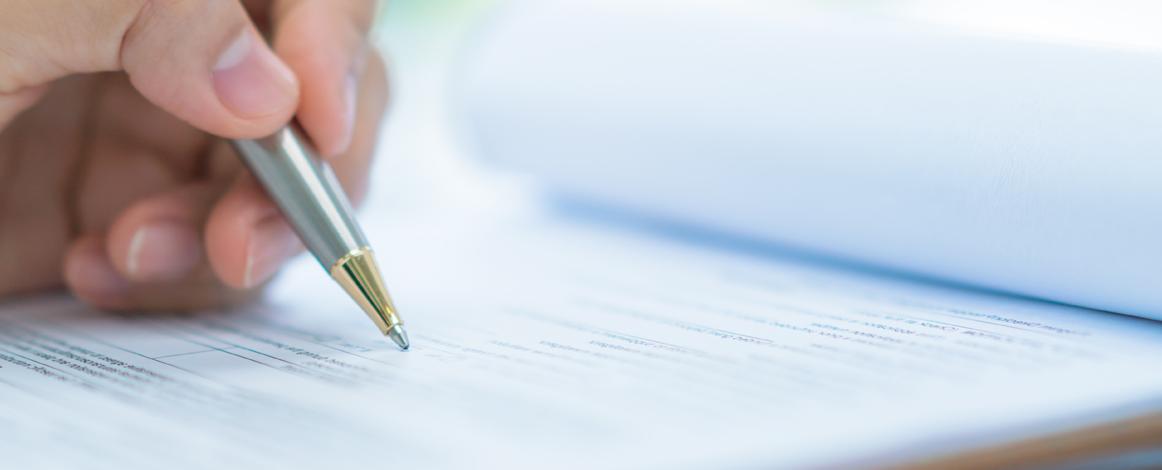 Closeup of hand with pen writing on paper form